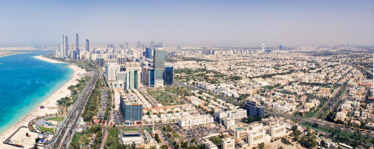 Aerial view of Abu Dhabi Corniche with beach and high-rise buildings, showing the city's modern and coastal lifestyle