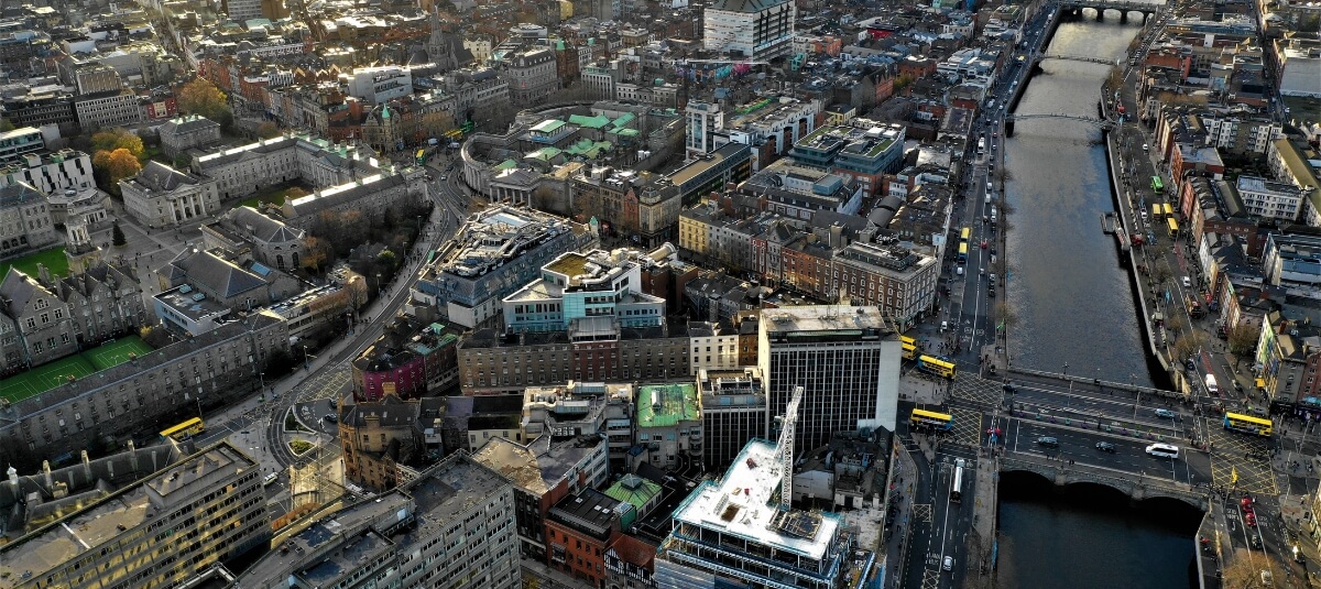 Wide aerial shot of Dublin city with the River Liffey, bridges, and surrounding buildings.