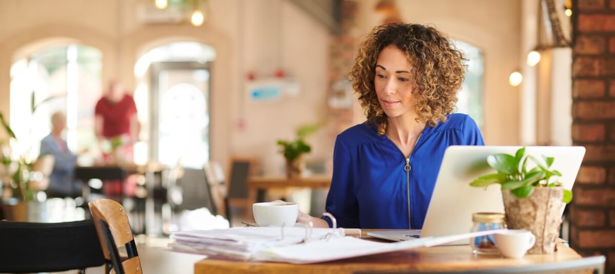 Professional expat woman working on a laptop with documents and coffee in a European café, symbolising career opportunities and tax-smart moves in Europe. Family loading boxes into removals van for international move with Total Moving Solutions