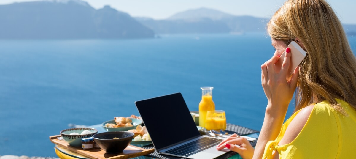Expat woman enjoying a Mediterranean lifestyle while working remotely by the sea, reflecting retirement and relocation to the best cities in Europe. Family with children unloading boxes from a removals van outside their new home after a long-distance move.