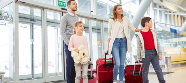 Family at airport with suitcases preparing to move abroad from the UK