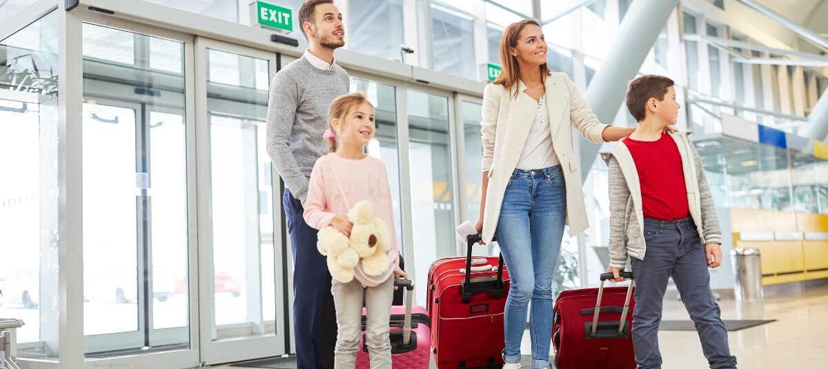 Family at airport with suitcases preparing to move abroad from the UK in 2025