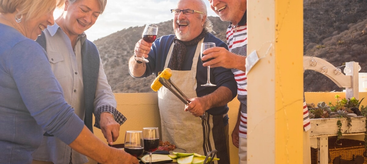 Group of retired UK expats enjoying wine and barbecue together overseas