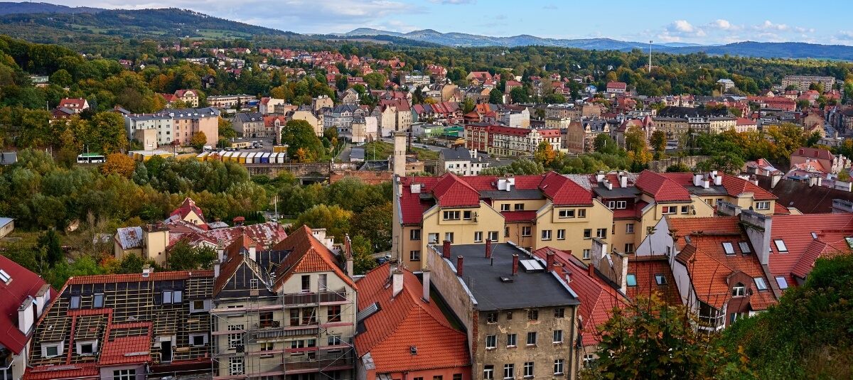 Scenic view of a Polish town with red rooftops and surrounding hills, showing typical homes for Brits moving to Poland from the UK. Scenic view of a Polish town with red rooftops and surrounding hills, showing typical homes for Brits moving to Poland from the UK.