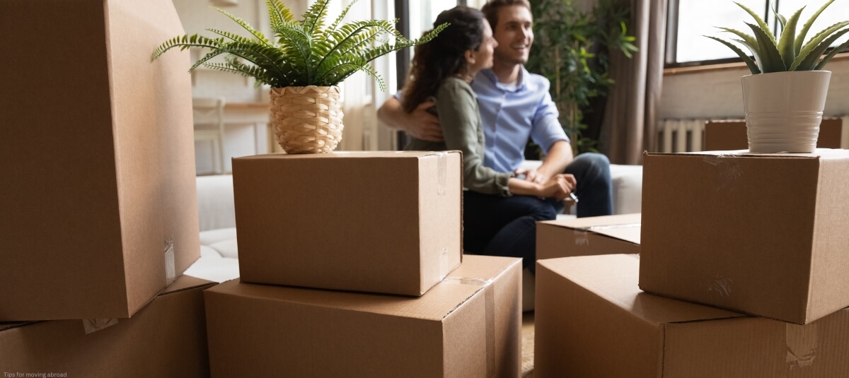 Young couple sitting in their new living room, surrounded by moving boxes, settling in after moving abroad. Young couple sitting in their new living room, surrounded by moving boxes, settling in after moving abroad.