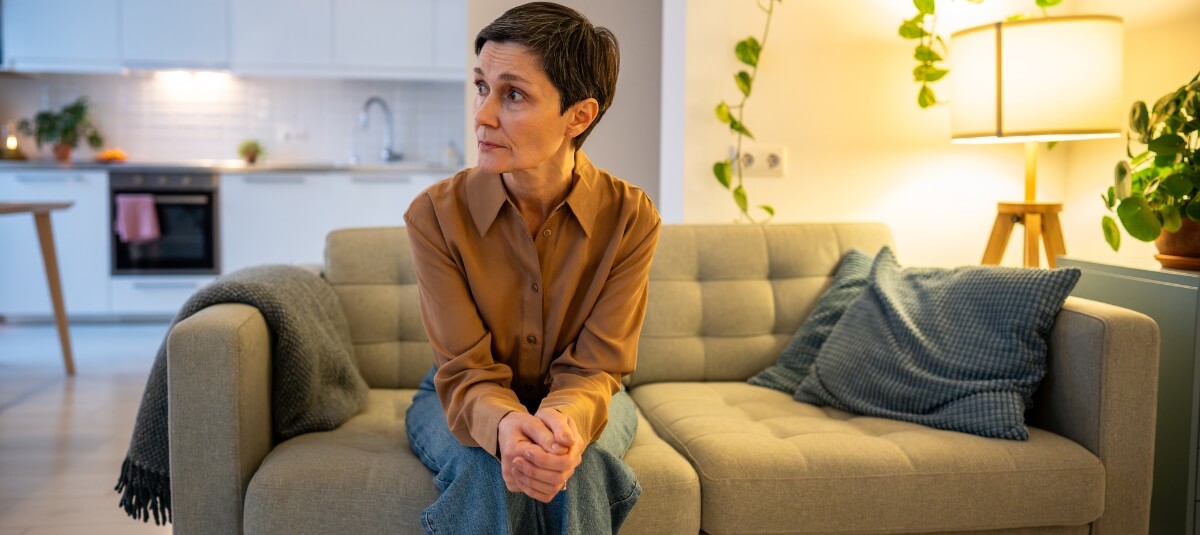 Woman sitting on a sofa in a cosy home, reflecting on the cultural adjustment and challenges of daily life in France. Woman sitting on a sofa in a cosy home, reflecting on the cultural adjustment and challenges of daily life in France.