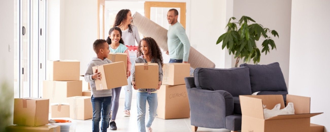 Family carrying moving boxes into their new home after moving to Norway from the UK