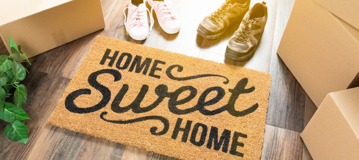 Home Sweet Home doormat with moving boxes and shoes, symbolising settling into a new home in Dublin.