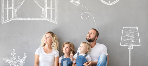 A family sitting together against a grey wall with hand-drawn illustrations of a window, clock, and lamp, symbolizing planning and aspirations for a new home.