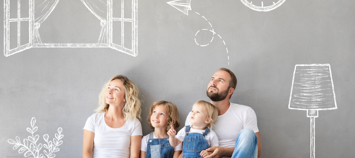 A family sitting together against a grey wall with hand-drawn illustrations of a window, clock, and lamp, symbolizing planning and aspirations for a new home. A family sitting together against a grey wall with hand-drawn illustrations of a window, clock, and lamp, symbolizing planning and aspirations for a new home.
