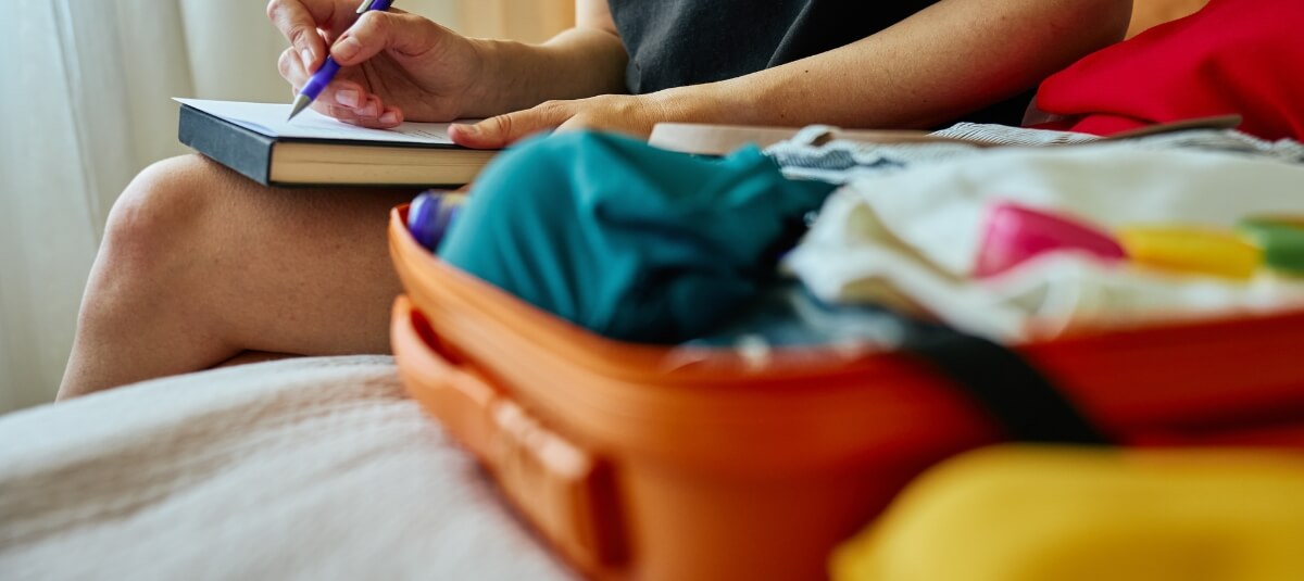 Woman writing a relocation checklist beside an open suitcase, symbolising the emotional and practical challenges of moving to a new town in the UK