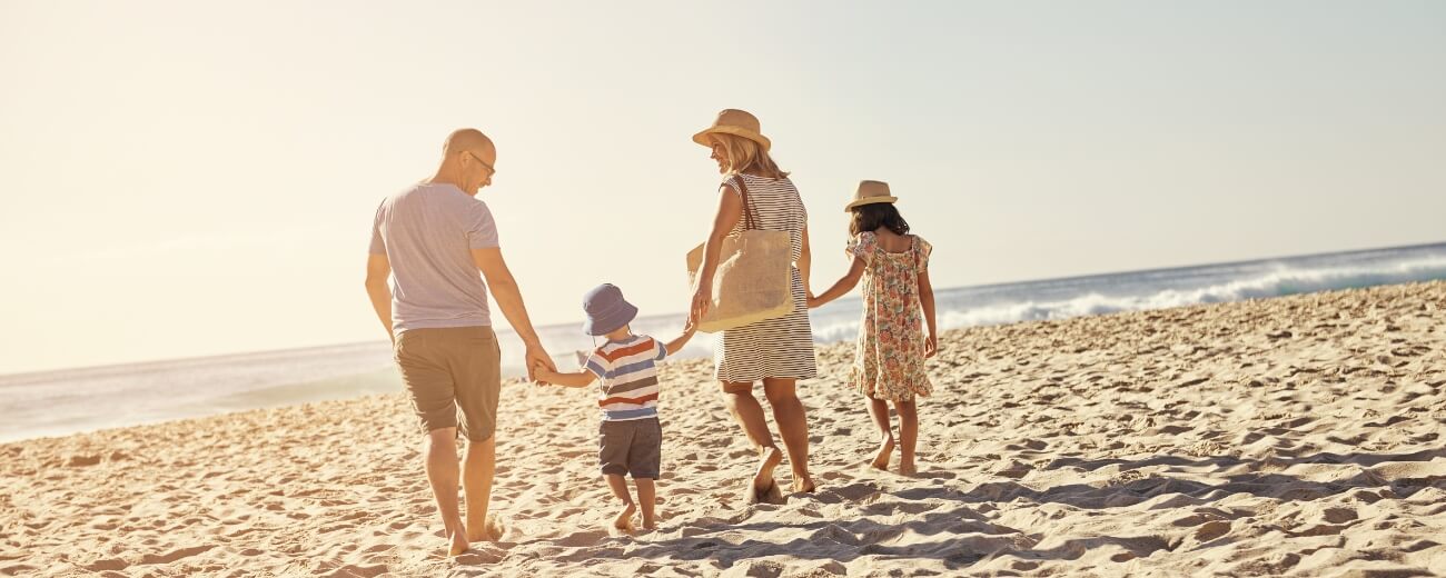 Family walking together on a sunny Australian beach after moving from the UK Family walking together on a sunny Australian beach after moving from the UK