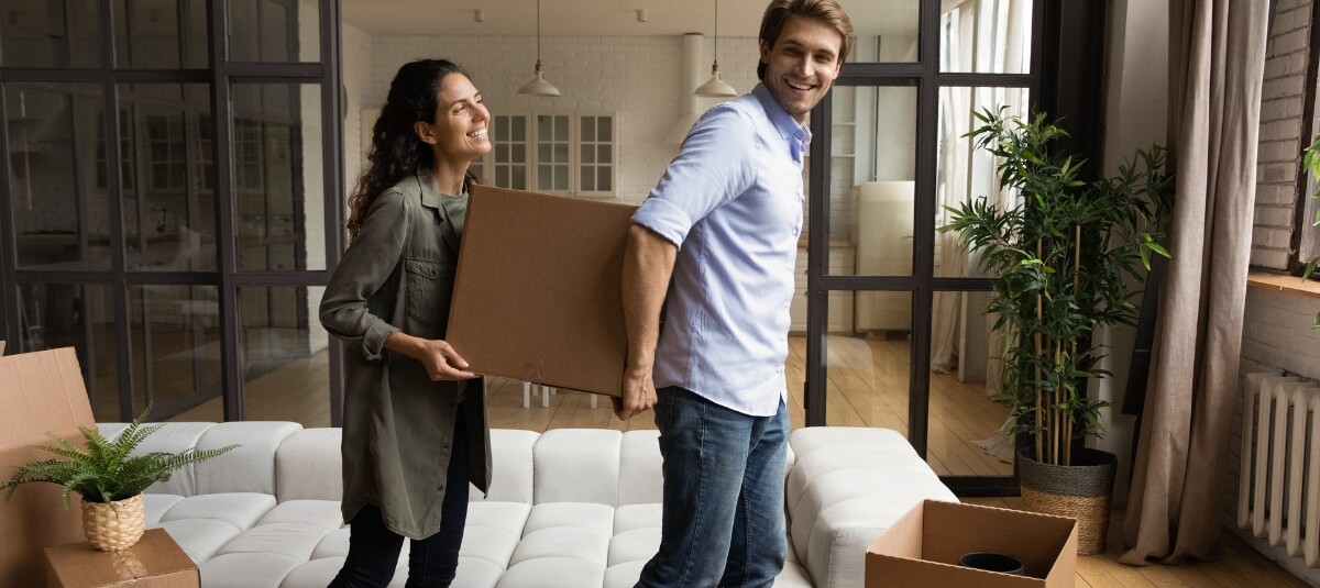 Couple carrying moving boxes into their new home after relocating from the UK to Spain