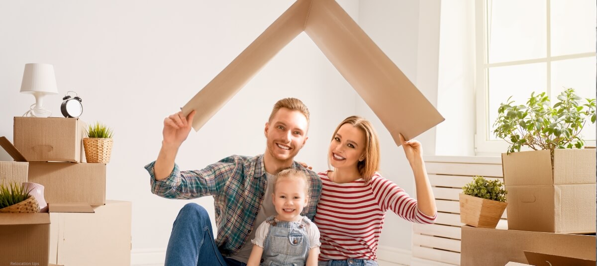 A cheerful family holding a cardboard roof shape over their heads, symbolising aspirations and planning for relocation. A cheerful family holding a cardboard roof shape over their heads, symbolising aspirations and planning for relocation.