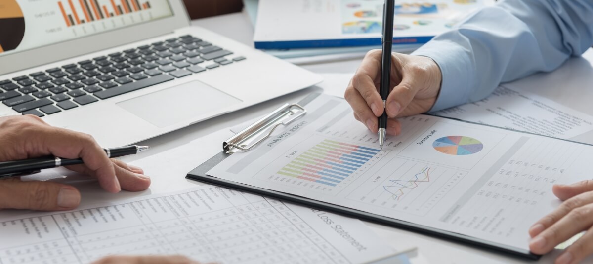 Close-up of financial charts and documents analysing Portugal’s return programme grants and 50% income tax benefits for citizens returning from the UK in 2026.