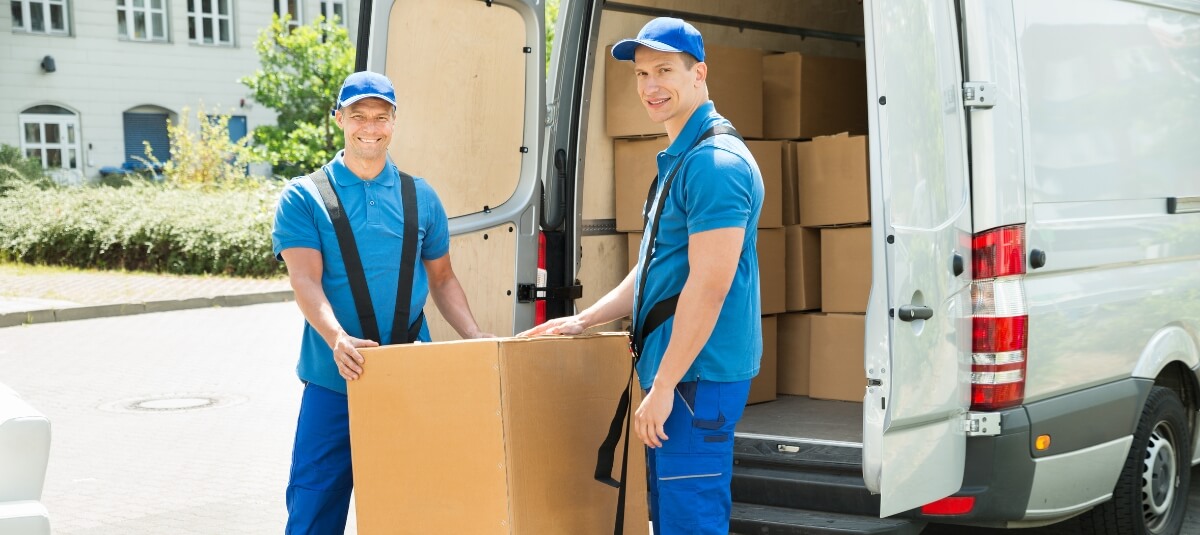 Removals crew delivering packed boxes to a residential property as part of a UK long distance move.