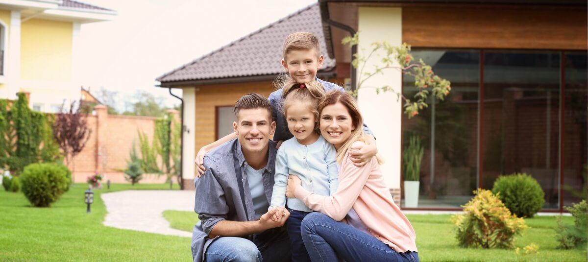 Family posing in front of their house with a lush garden, showcasing the benefits of spacious living after moving to the USA from the UK.