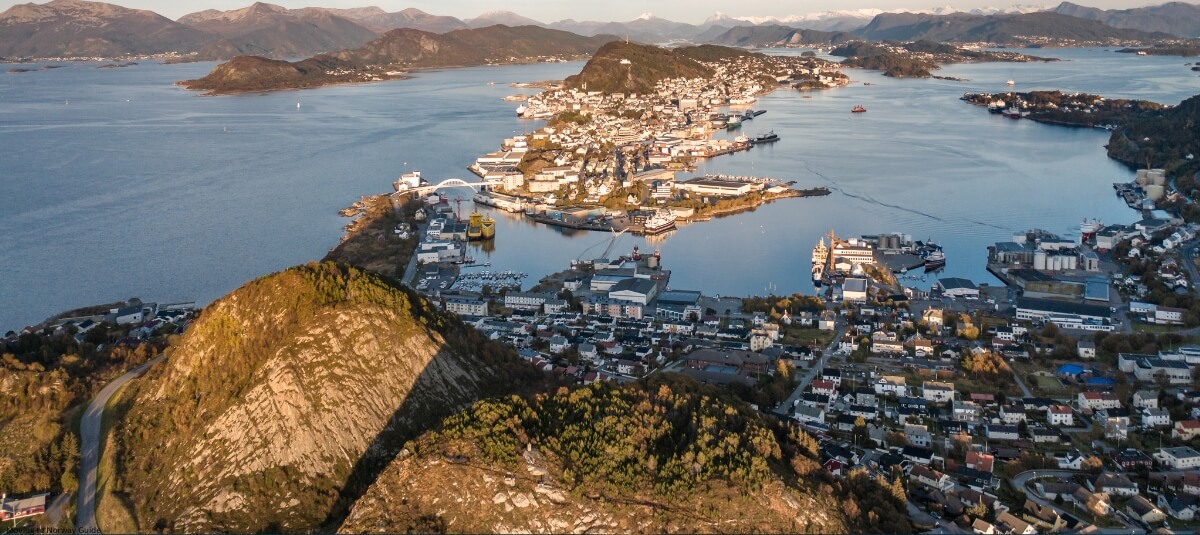An aerial view of a coastal town in Norway, showcasing the scenic beauty of the fjords, mountainous terrain, and a well-developed town nestled by the water—ideal for those considering relocation to Norway for its stunning landscapes and high quality of life. An aerial view of a coastal town in Norway, showcasing the scenic beauty of the fjords, mountainous terrain, and a well-developed town nestled by the water—ideal for those considering relocation to Norway for its stunning landscapes and high quality of life.