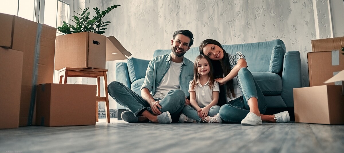 A family sitting together in a cosy living room with unpacked moving boxes, symbolising a fresh start in a new home. A family sitting together in a cosy living room with unpacked moving boxes, symbolising a fresh start in a new home.