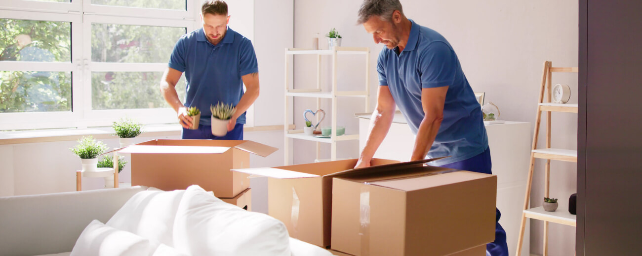 Two removals team members packing household goods into boxes before a move from the UK to India