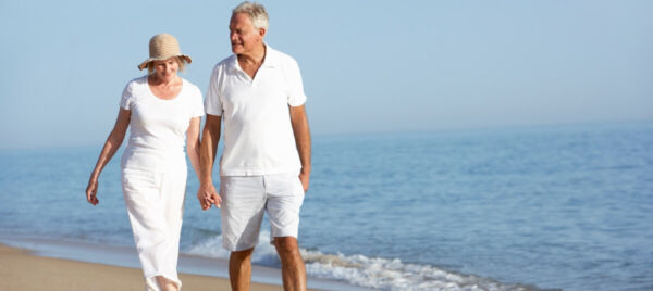 Retired British couple walking on a sunny beach abroad – symbolising retirement lifestyle for UK expatsRetired British couple walking on a sunny beach abroad – symbolising retirement lifestyle for UK expats