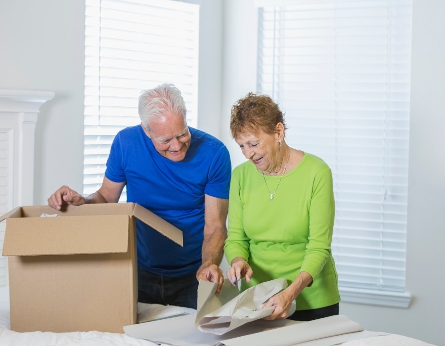 Senior couple packing boxes before retiring abroad Senior couple packing belongings into a moving box at home