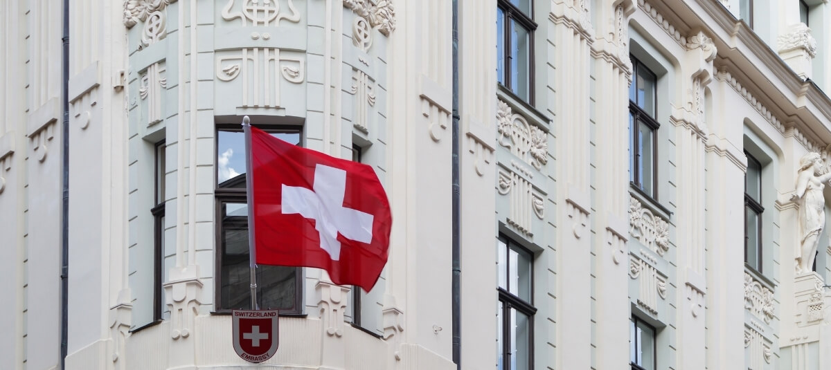 Swiss embassy building with national flag, representing 2026 visa and residency requirements for UK citizens moving to Switzerland. Swiss embassy building with national flag, representing 2026 visa and residency requirements for UK citizens moving to Switzerland.