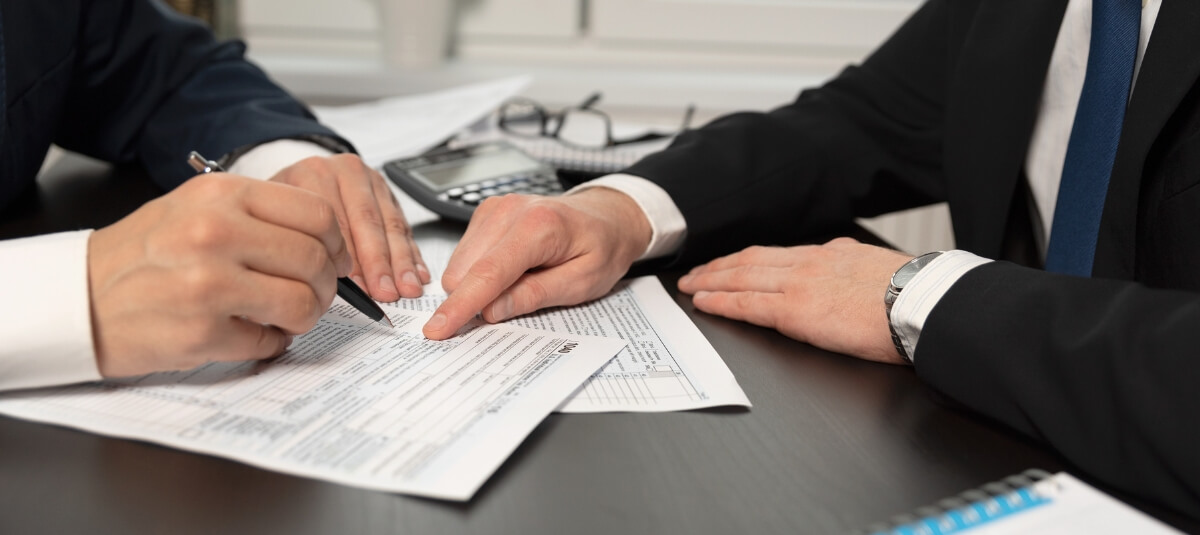 Two people reviewing and signing international moving documents, such as customs forms or HMRC paperwork for moving overseas. Two people reviewing and signing international moving documents, such as customs forms or HMRC paperwork for moving overseas.